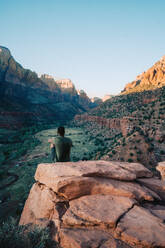 Black man fitted on a rock contemplating the mountain during sunset - CAVF71361