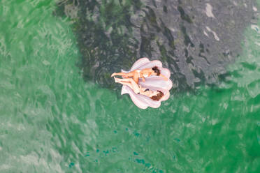 Luftaufnahme von zwei attraktiven Mädchen, die mit einem Schlauchboot in der Gordons Bay schwimmen, Sydney, Australien. - AAEF06113