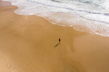 Luftaufnahme einer Frau, die allein am versteckten Strand von Alexandria Bay, Australien, spazieren geht. - AAEF06130