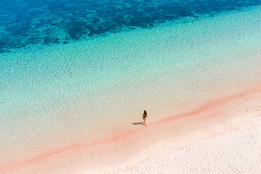 Luftaufnahme einer attraktiven Frau, die am rosa Strand spazieren geht, Padar-Inseln, Indonesien. - AAEF06204