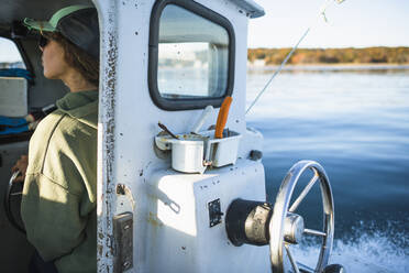 Woman driving shellfishing boat on Narragansett Bay - CAVF71466