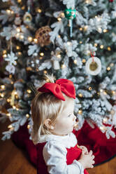 Junges Mädchen schaut aus dem Fenster neben dem Weihnachtsbaum - CAVF71704
