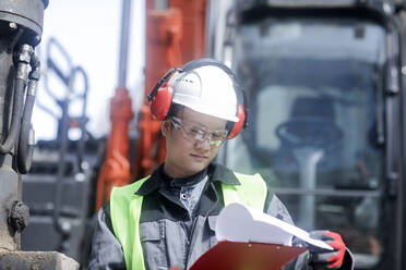 Bauingenieur vor einem Bagger stehend - CAVF71783