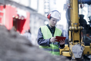 Civil engineer standing in front of an excavator - CAVF71786