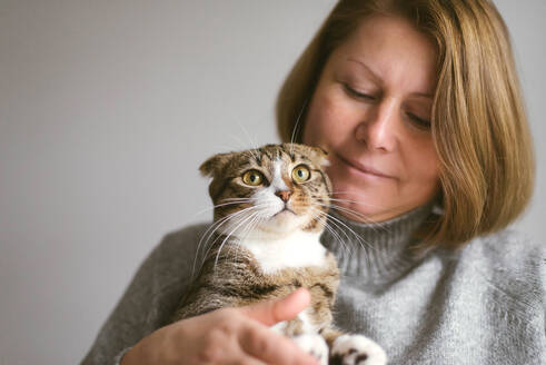 Frau hält schöne Katze auf weißem Hintergrund - CAVF71817