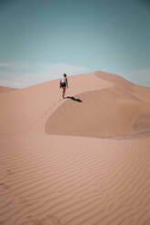 Junge Frau wandert auf einer Wüstendüne und hinterlässt Fußspuren im Sand - CAVF71821