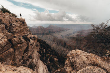 Young woman overlooking Grand Canyon while a thunderstorm approaches - CAVF71823