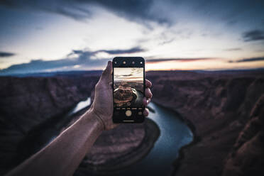 Young Man holding iPhone, photographing sunset at Horseshoe Bend - CAVF71827