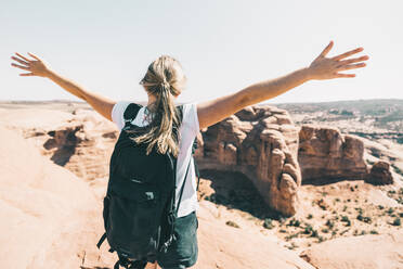 Wide-angle shot of a young woman spreading arms over a canyon lookout - CAVF71828