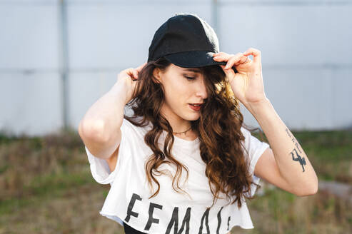 Attractractive millennial woman with long curly hair wearing a cap - CAVF71835