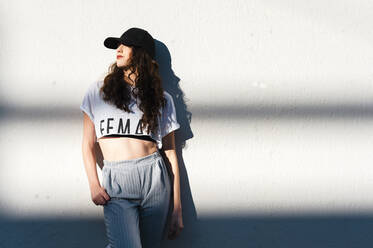 Attractive trendy woman leaning on white wall with horizontal shadows - CAVF71838