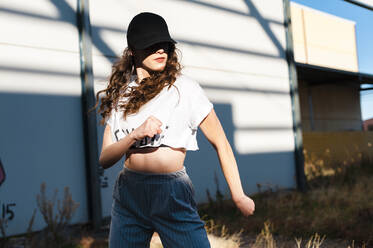 Millennial woman with long curly hair dancing in abandoned building - CAVF71841