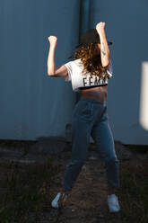 Excited dancer shaking hands performing dance pose in urban area - CAVF71845