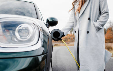 Frau beim Anschließen ihres Elektroautos Mini Countryman - CAVF71925