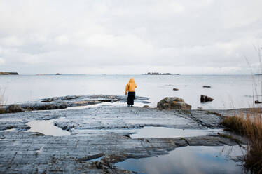 Kind steht auf einem Felsen und blickt auf das Meer in den schwedischen Schären - CAVF71938