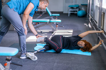 Personal trainer assisting woman with disabilities in her workout - CAVF72007