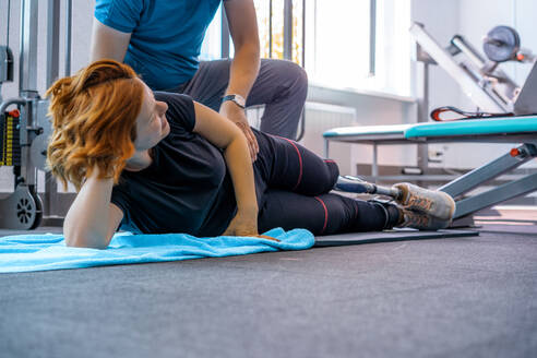 Personal Trainer, der einer Frau mit Behinderung beim Training hilft - CAVF72010