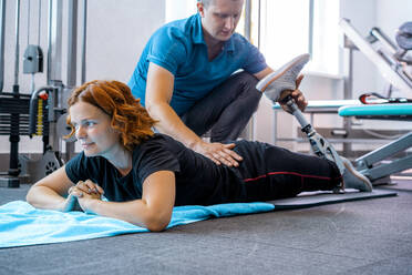 Personal trainer assisting woman with disabilities in her workout - CAVF72012