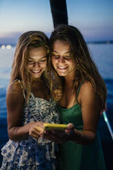 Freunde auf einem Segelboot, Textnachrichten austauschen, Italien - CUF54177