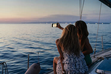 Friends taking selfie on sailboat, Italy - CUF54182