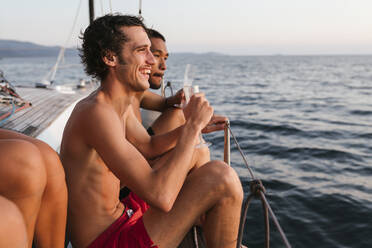 Junge Männer genießen Champagner auf einem Segelboot, Italien - CUF54187