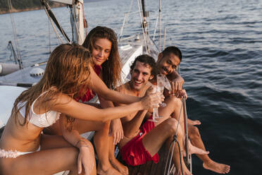 Friends toasting with champagne on sailboat, Italy - CUF54188