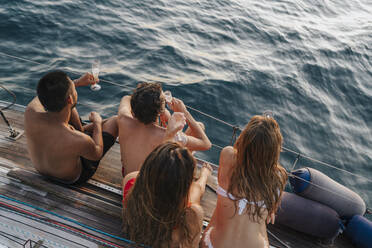 Friends enjoying champagne on sailboat, Italy - CUF54189