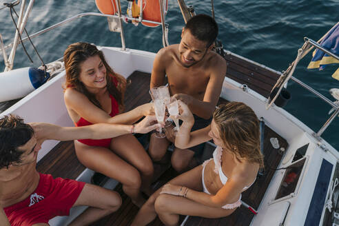 Freunde stoßen mit Champagner auf einem Segelboot an, Italien - CUF54190