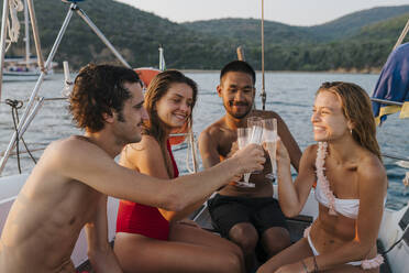 Freunde stoßen mit Champagner auf einem Segelboot an, Italien - CUF54192