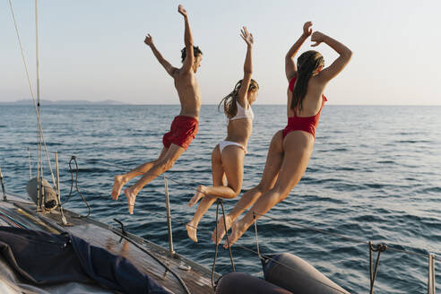 Freunde springen von einem Segelboot ins Meer, Italien - CUF54193