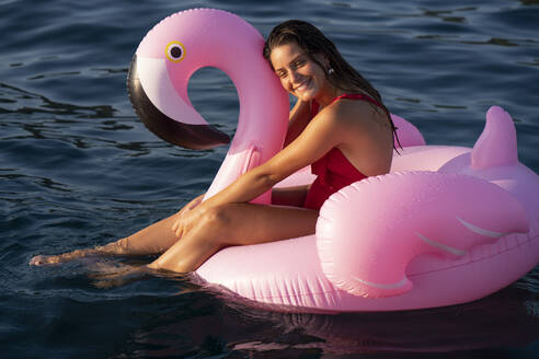 Frau auf Flamingo-Schwimmer auf dem Meer, Italien - CUF54195