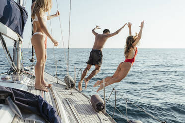 Freunde springen von einem Segelboot ins Meer, Italien - CUF54200