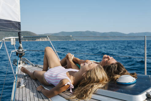 Freunde beim Sonnenbaden auf dem Deck eines Segelboots, Italien - CUF54221