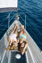 Freunde beim Sonnenbaden auf dem Deck eines Segelboots, Italien - CUF54223