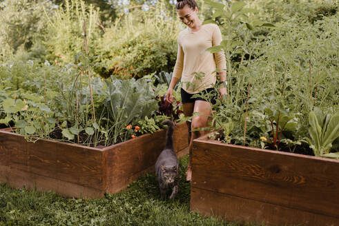 Woman gardener with cat in garden - CUF54250