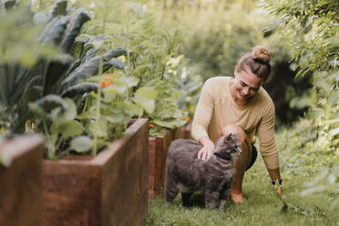 Gärtnerin mit Katze im Garten - CUF54251