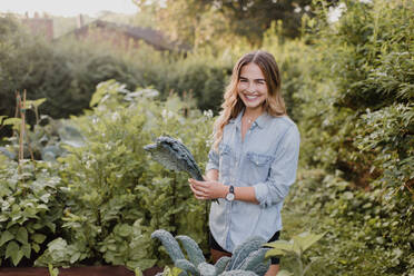Frau bei der Arbeit an Pflanzen und Gemüse in ihrem Garten - CUF54280
