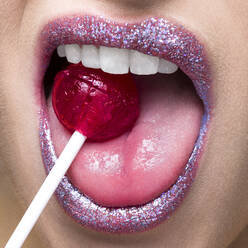 Shimmering lips biting on lollipop - ISF23361
