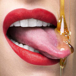 Rote Lippen mit Zunge, die triefenden Honig auffängt - ISF23364