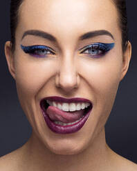 Schöne junge Frau mit vollem Make-up streckt die Zunge heraus - ISF23385
