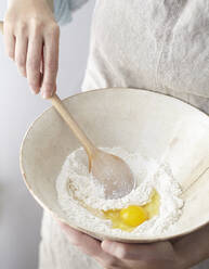 Midsection of woman mixing flour and egg in bowl - CAVF72323