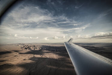 Ausgeschnittenes Bild eines Flugzeugflügels, der über die Landschaft fliegt - CAVF72364