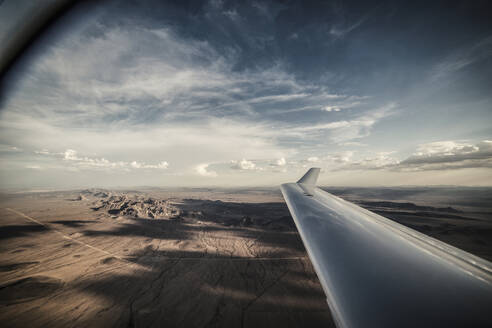 Ausgeschnittenes Bild eines Flugzeugflügels, der über die Landschaft fliegt - CAVF72364