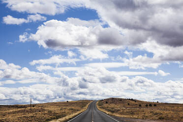 High angle view of country road amidst field against cloudy sky - CAVF72388