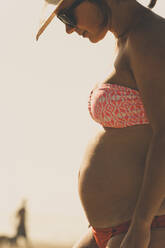 Side view of pregnant woman wearing bikini while standing at Sunset Bay State Park - CAVF72405