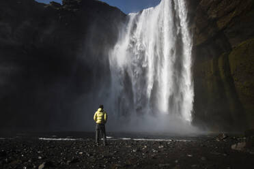 Rear view of man looking at waterfall - CAVF72419