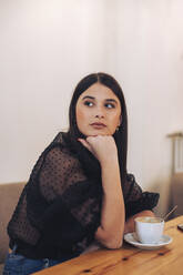 Brunette woman sitting in a cafe drinking coffee - ACPF00645