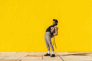 Young man dancing in front of yellow wall - AFVF04527