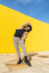 Junger Mann tanzt vor einer gelben Wand - AFVF04537