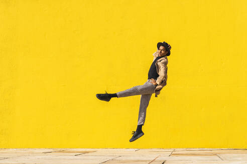 Junger Mann tanzt vor einer gelben Wand und springt in der Luft - AFVF04547